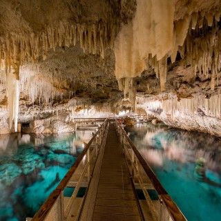 the inside of a cave with blue water and large caves on either side that are filled with stalate formations