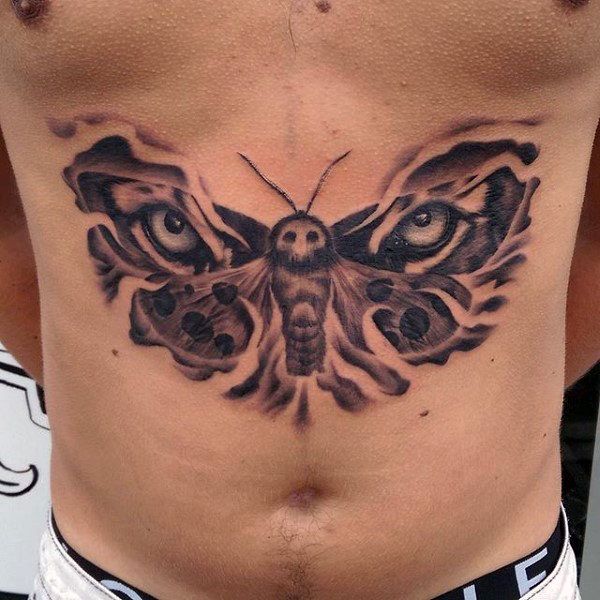 a man's stomach with a butterfly tattoo on his chest and eyes in the center