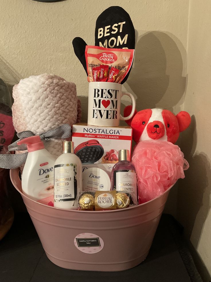 a pink basket filled with bath products and other items on a table next to a wall