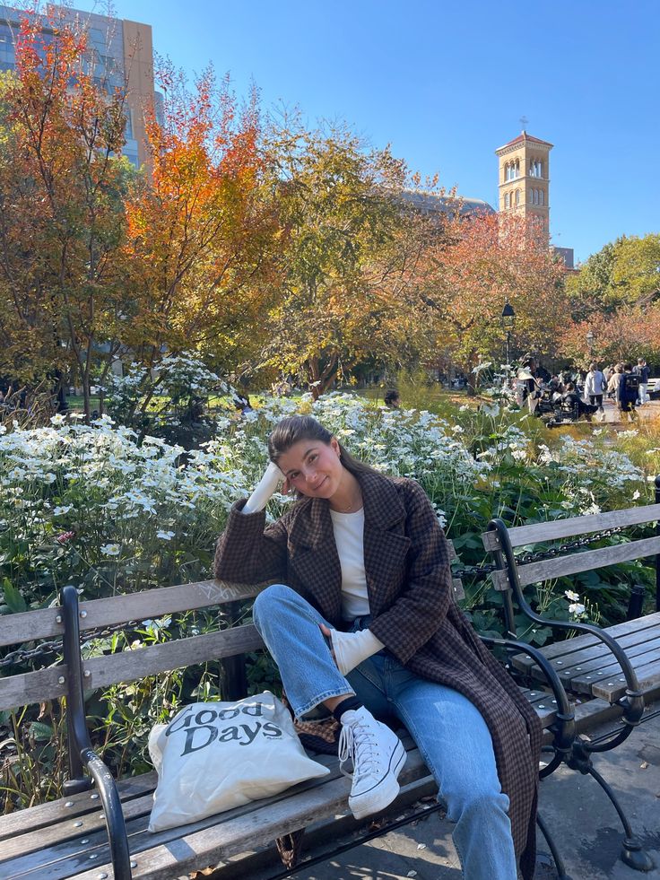 a woman is sitting on a bench in the park