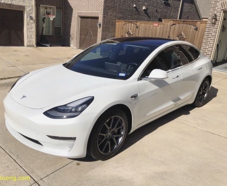 a white tesla parked in front of a house