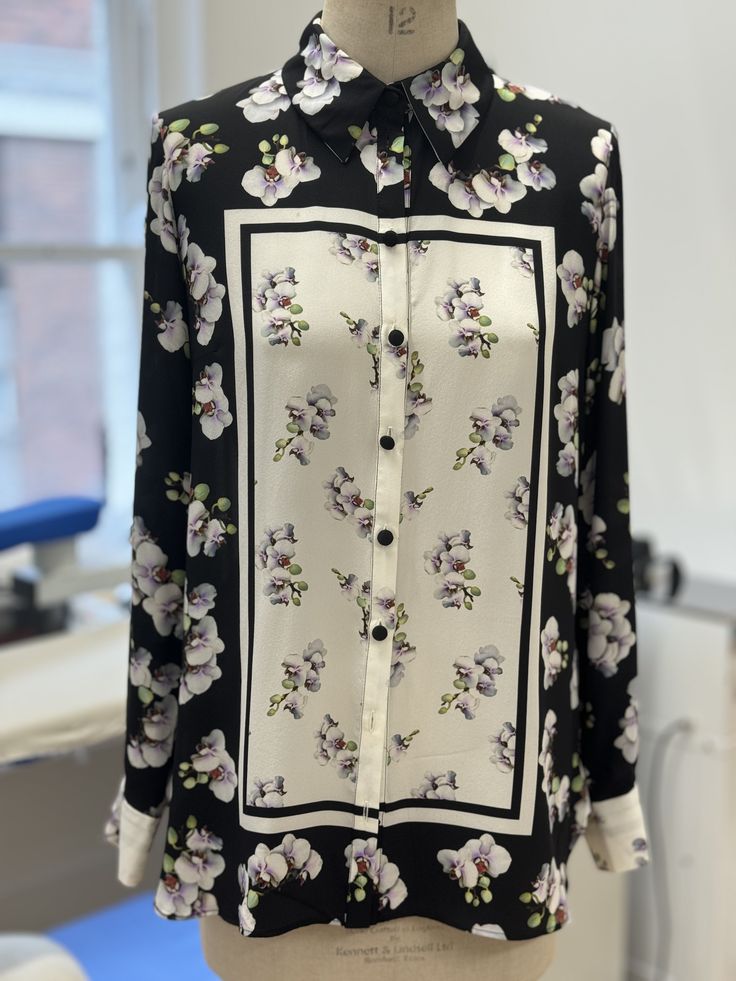 The Shutters Classic Silk Shirt is a button-through Italian silk crepe de chine shirt with a stunning monochrome placement orchid print. The beautiful orchids are painted by Kate Scott, a botanical digital fine artist who has worked with Suzannah for 10 years. Kate paints the flowers with a digital tool at high resolution, with the florals appearing clearer than a photograph, as if they can be plucked from the cloth. Kate's work has been exhibited globally and in the Saatchi gallery. Expertly printed by a premium mill in Italy, the absolute finest techniques were used to translate this incredible art onto the beautiful silk crepe. Featuring full length cuffed sleeves, simple silk covered buttons, and a deep box pleat at the back, the Shutters Shirt has a beautiful elegance and fluidity to