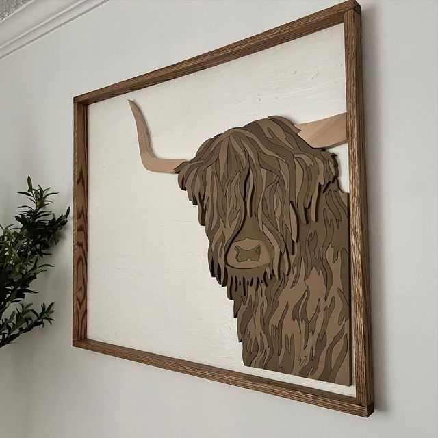 a painting of a bison is hanging on the wall next to a potted plant