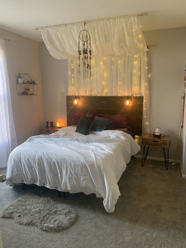 a bed with white sheets and lights hanging from the headboard in front of a window