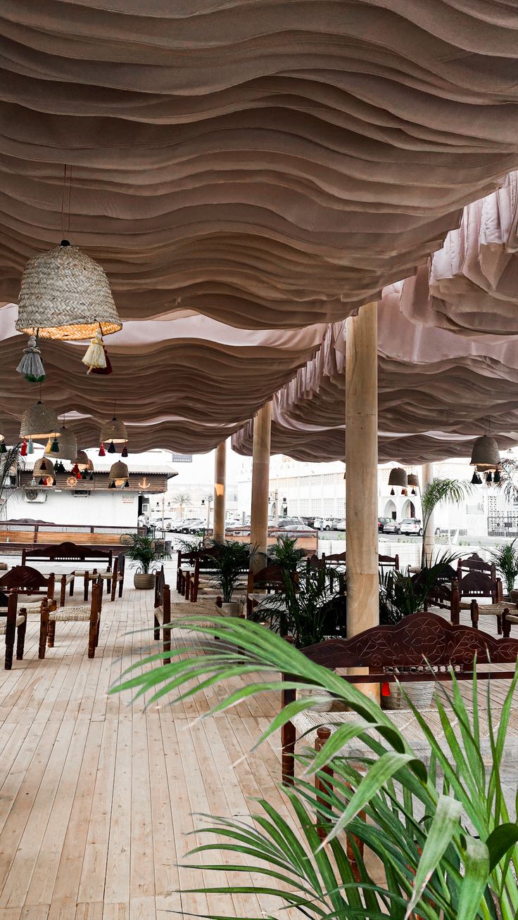 the inside of a restaurant with wooden tables and chairs under an umbrella covered roof,