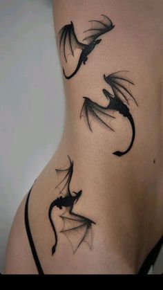 a woman's back with black dragon tattoos on her stomach and the bottom part of her body