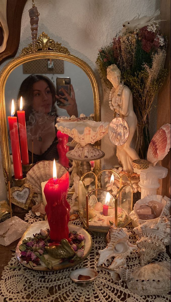 a woman taking a selfie in front of a table with candles and other items