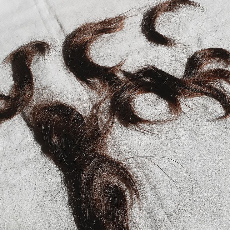 some hair that is laying on top of a bed sheet with it's ends curled up