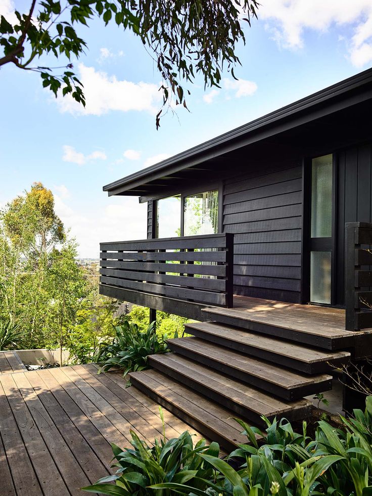 there is a black house with wooden steps leading up to the front door and windows