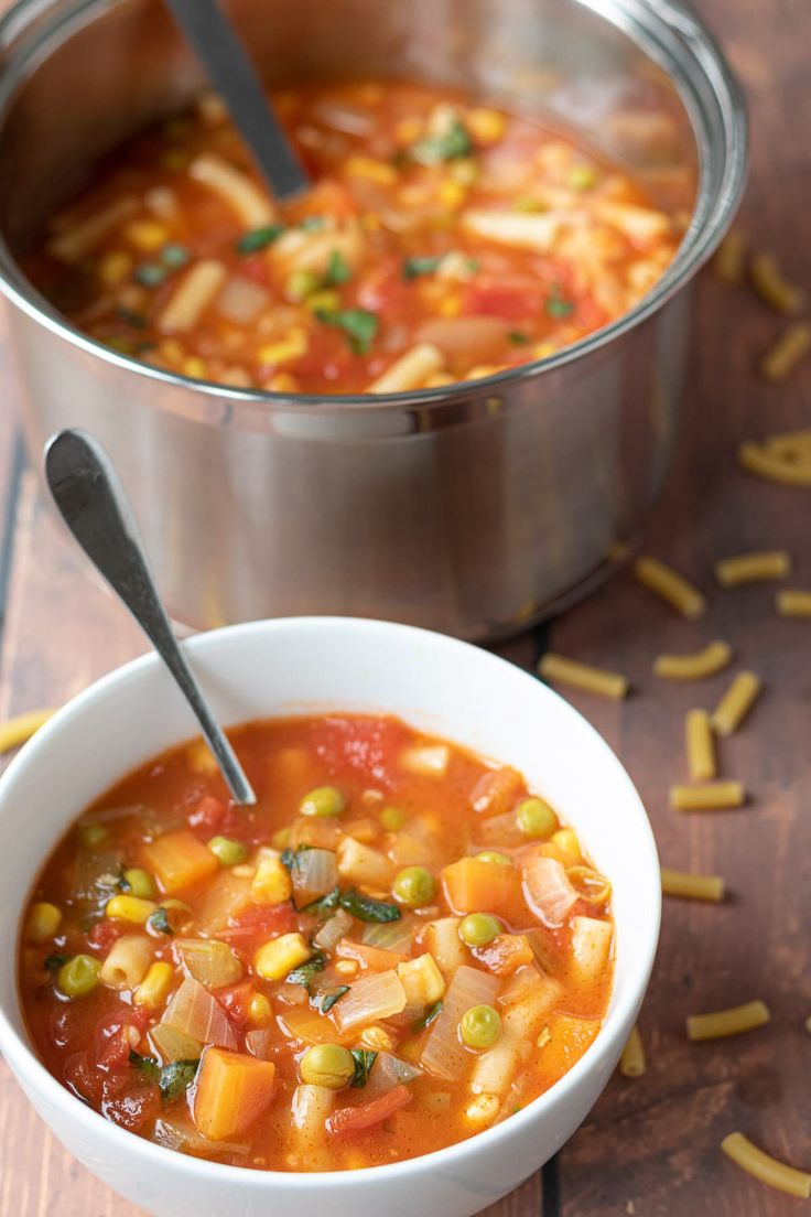 two bowls filled with soup on top of a wooden table next to a metal pot