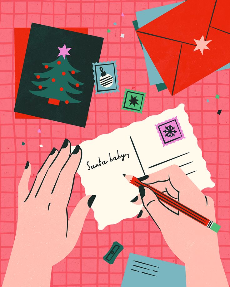 two hands are writing on a piece of paper with christmas decorations around it and an envelope in the foreground