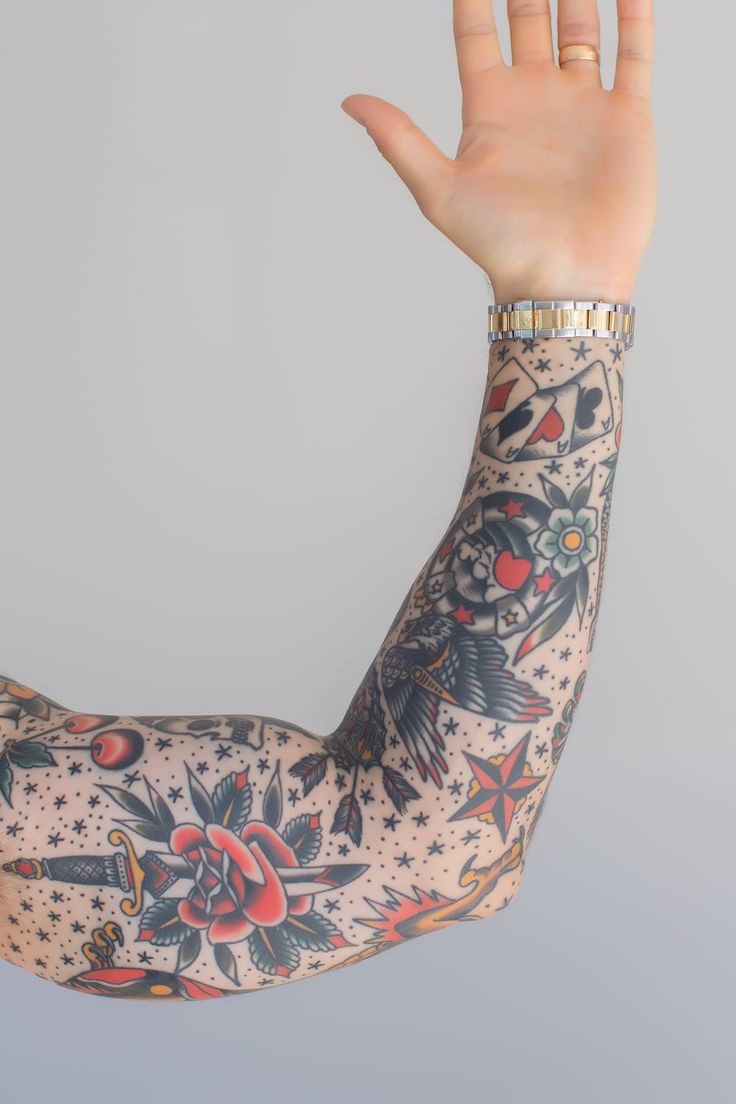 a woman's arm with tattoos on it and her hand up to the sky