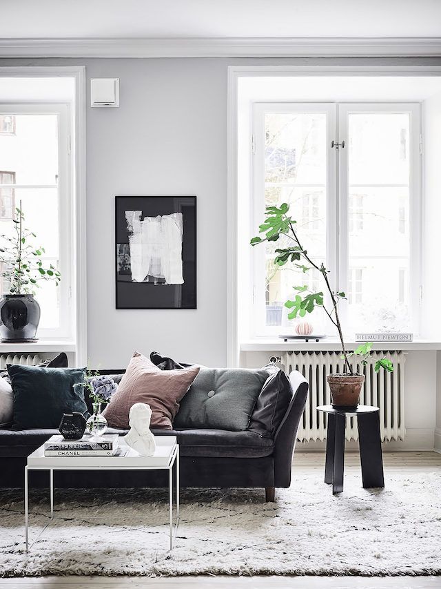 a living room filled with lots of furniture next to two windows and a rug on the floor