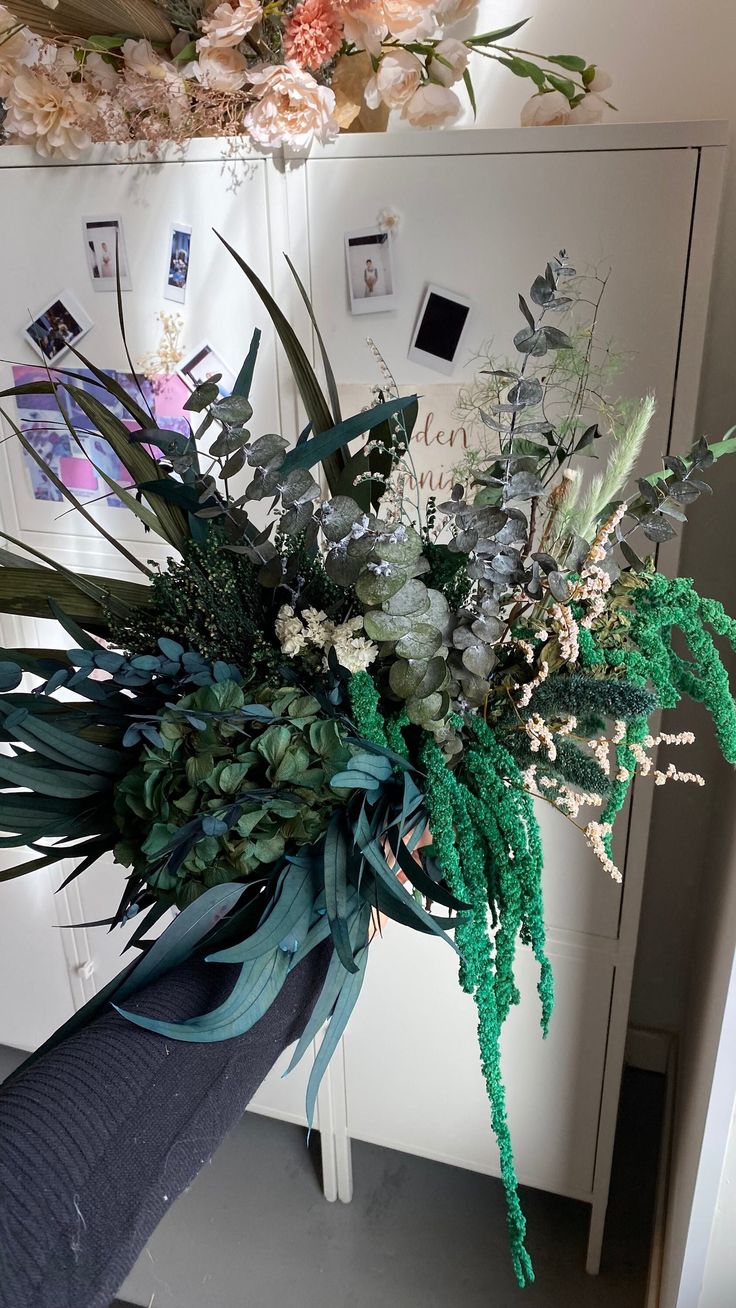 a bouquet of flowers sitting on top of a white table next to a freezer