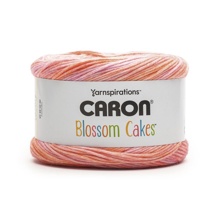 yarn with pink and orange colors on the top, in a white container that says caron blossom cakes