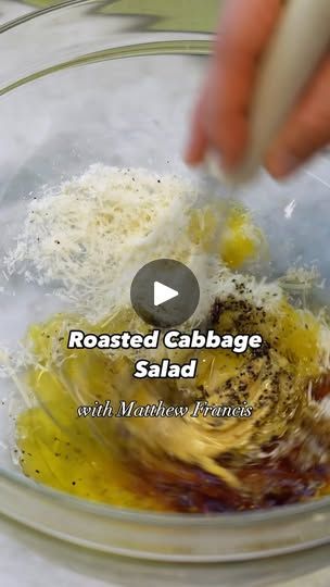 someone mixing ingredients in a glass bowl with the words roasted cabbage salad written below it