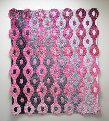 a pink and black quilt hanging on the wall