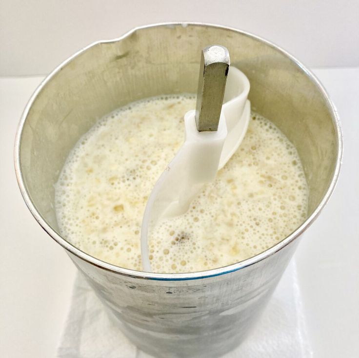 a metal bowl filled with white liquid and a whisk in the top right corner