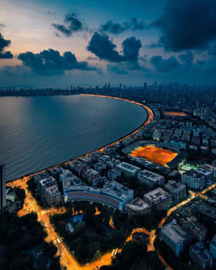 an aerial view of a city at night with lights on the water and buildings in the background