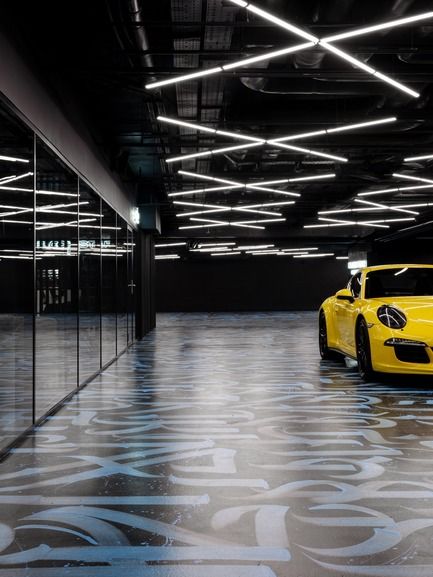 a yellow sports car is parked in an empty parking garage with lights on the ceiling