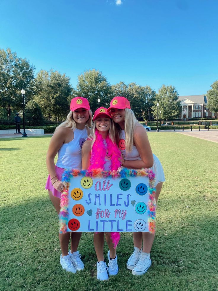 three girls in pink hats holding a sign that says, all smiles for my little