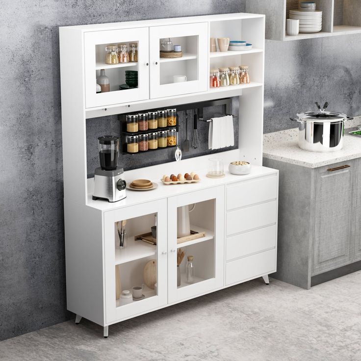 a kitchen with white cupboards and appliances on the counter top, next to a gray wall