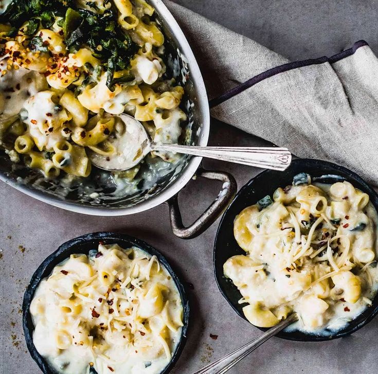 two skillets filled with macaroni and cheese on top of a gray table