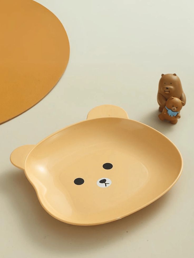 a bear shaped dish next to a small toy bear