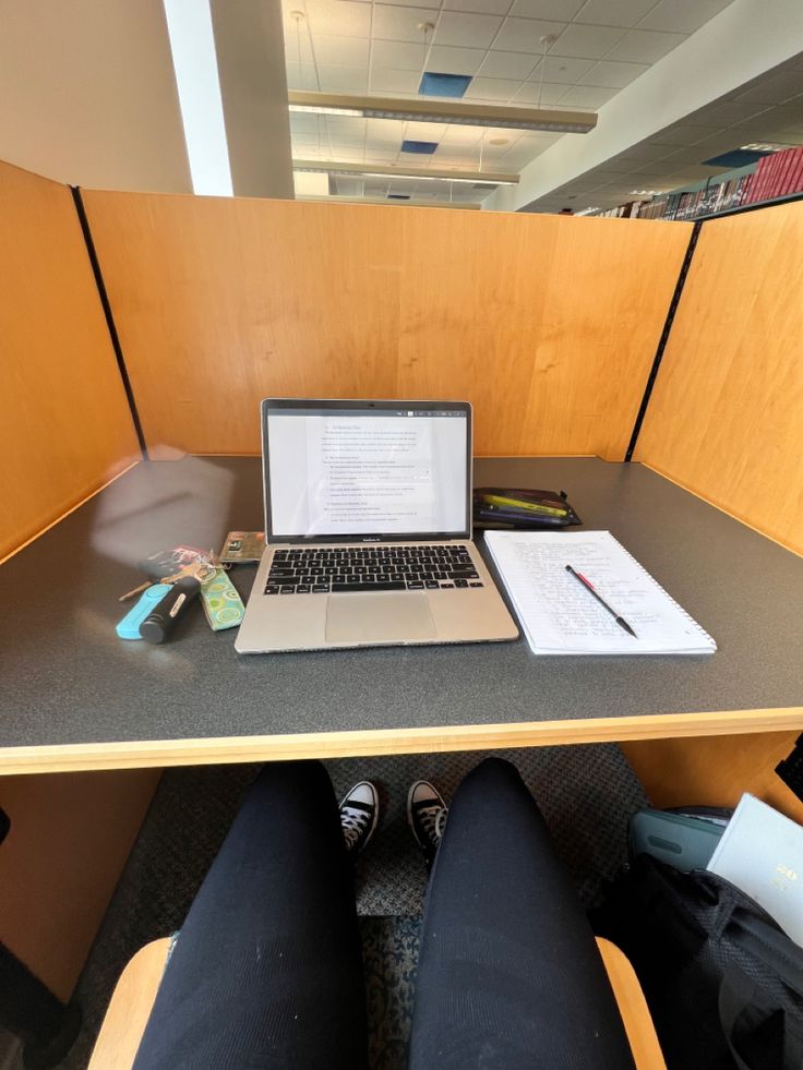 an open laptop computer sitting on top of a desk next to a pair of black pants