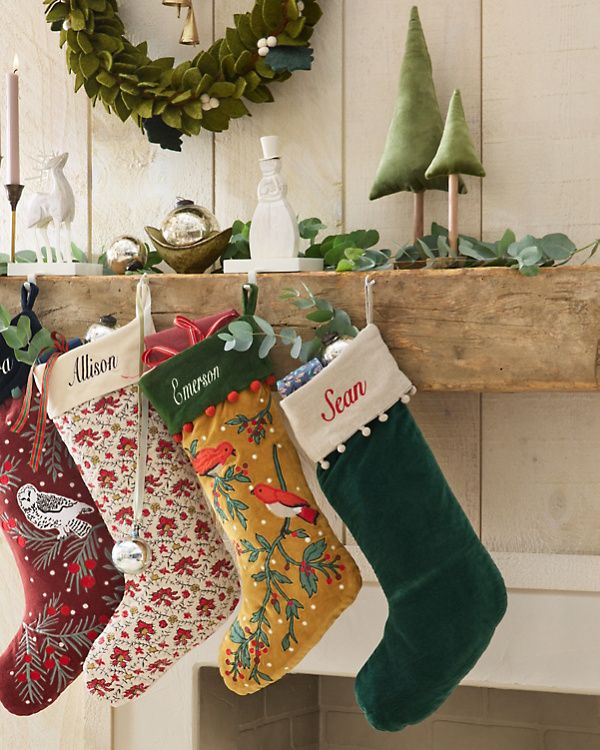 three stockings hanging from a mantel decorated with christmas decorations