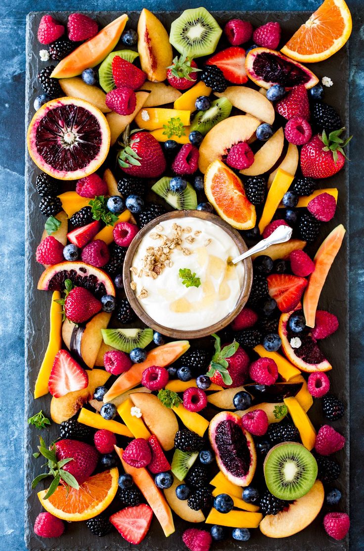 a bowl of yogurt surrounded by fresh fruit