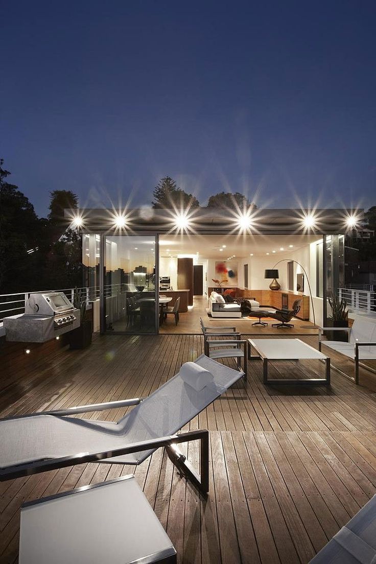 an outdoor living area with furniture and lights on the roof terrace at night, lit up by floodlights