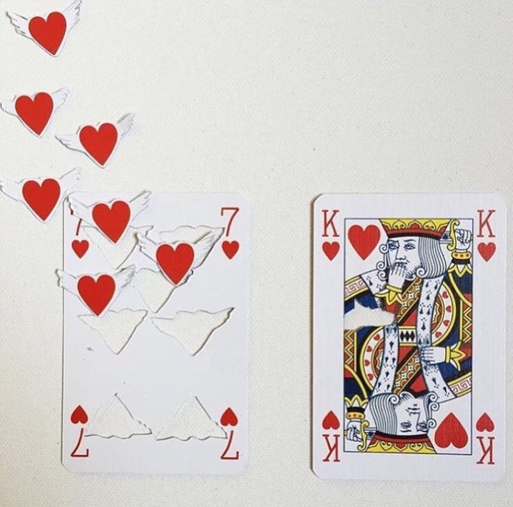 playing cards with hearts on them sitting next to each other in front of a white wall