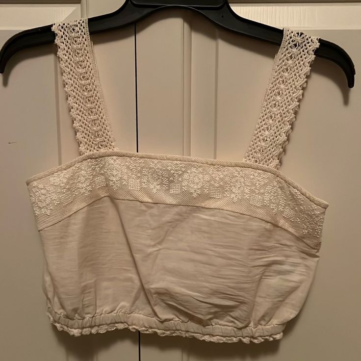 Like New, Never Worn. Fits Like A Small. Cream Or Off White Color, Crochet Straps. Elastic Band Around Ribs White Cotton Crochet Top For Spring, White Cotton Crop Top For Vacation, Cream Cotton Crochet Top, White Casual Crochet Top With Lace Trim, Casual White Crochet Top With Lace Trim, White Fitted Cotton Crochet Top, Beige Lace Sleeveless Crop Top, Beige Cotton Tops With Crochet Trim, Spring Cotton Lace Crop Top