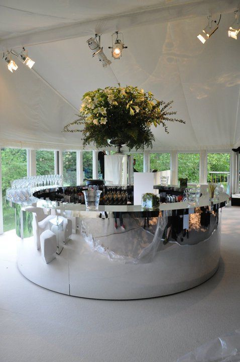 a round table with chairs and a plant in the center is surrounded by white walls