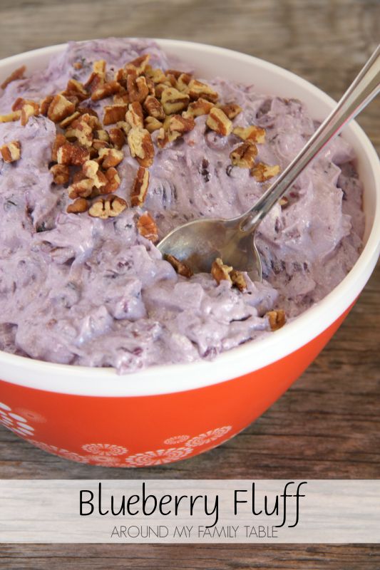 a bowl of blueberry fluff with a spoon in it on a wooden table