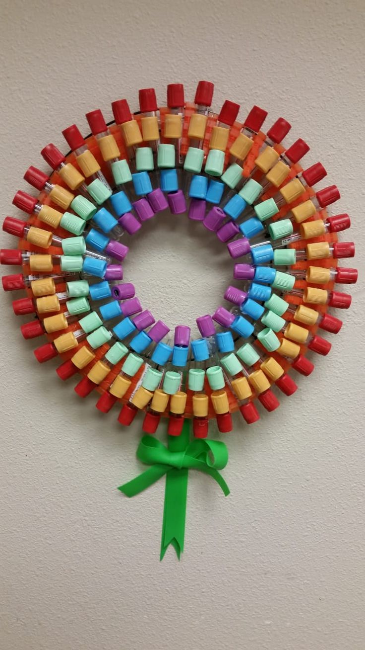 a wreath made out of colored crayons with a green bow on the side