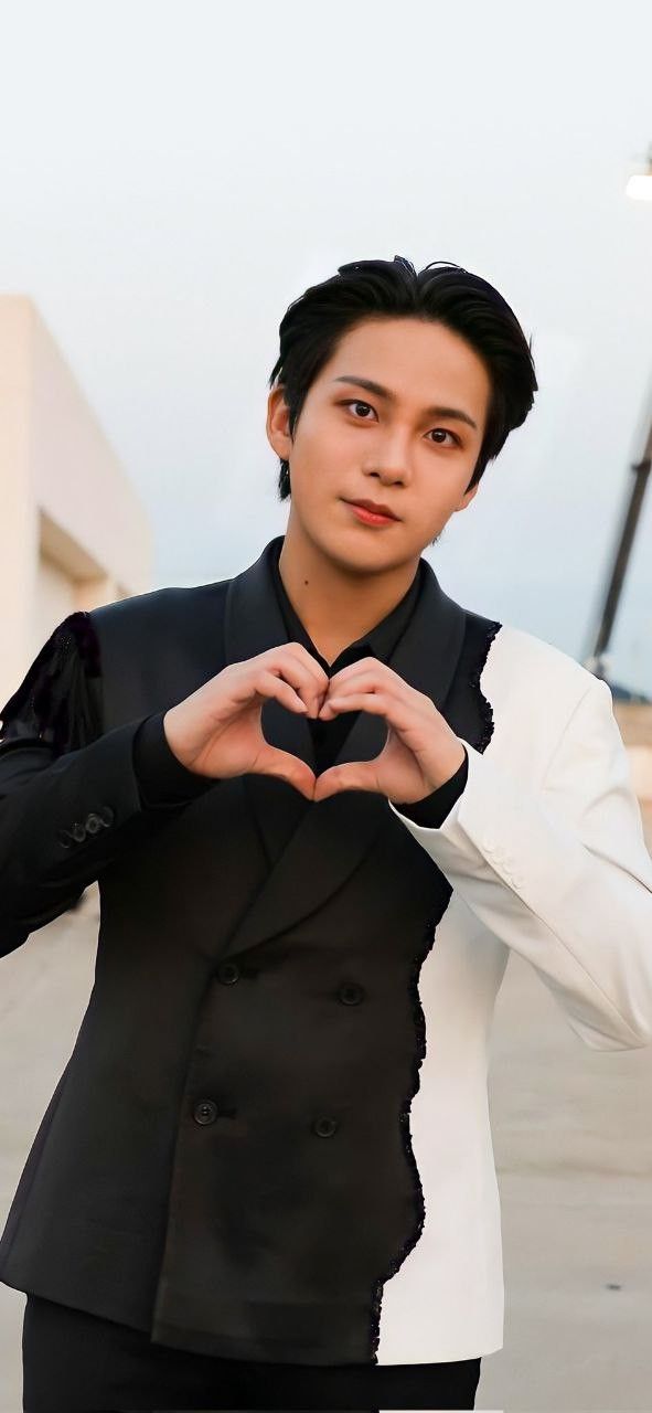 a young man in a suit making a heart with his hands