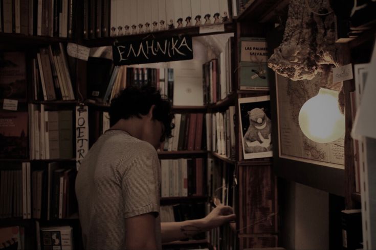 a man standing in front of a book shelf filled with books