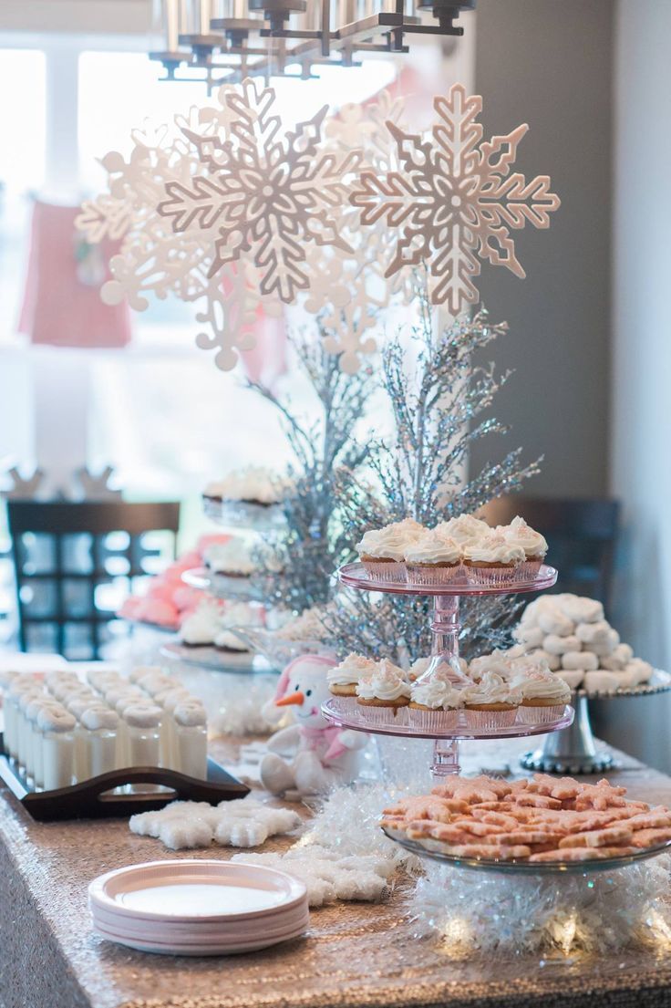 a table topped with lots of desserts next to a snowflake decoration on top of a cake stand