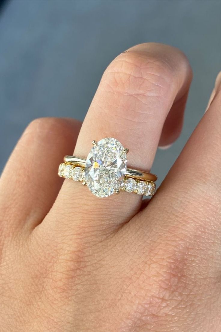 a woman's hand with a diamond ring on top of her finger and the engagement band