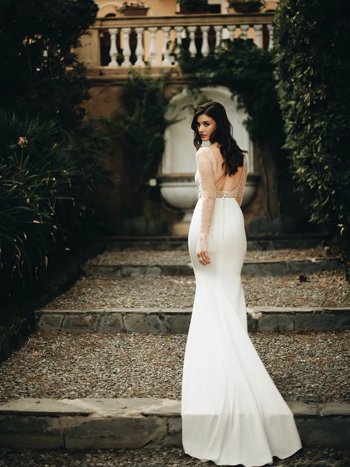 a woman in a white wedding dress standing on some steps with her back to the camera