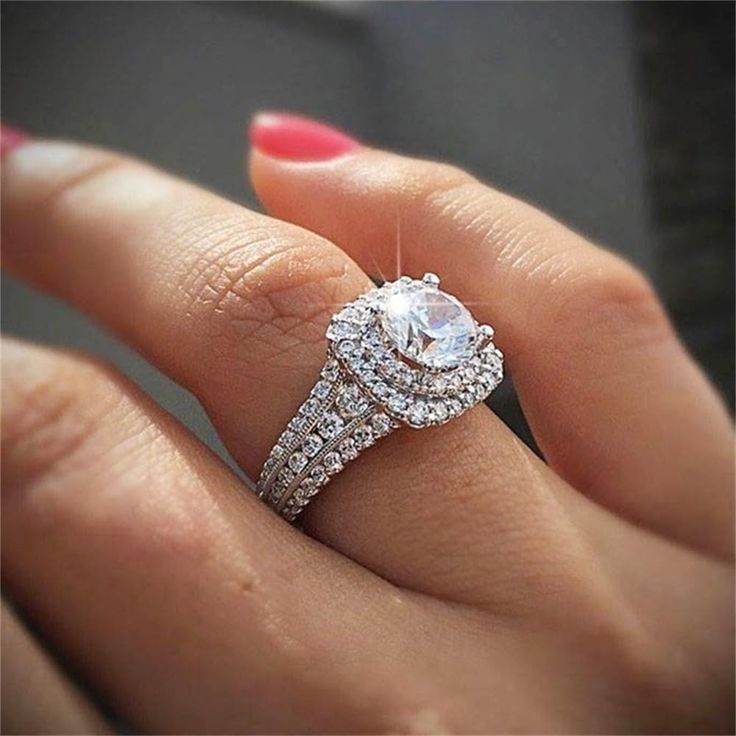 a woman's hand holding an engagement ring with two rows of diamonds on it