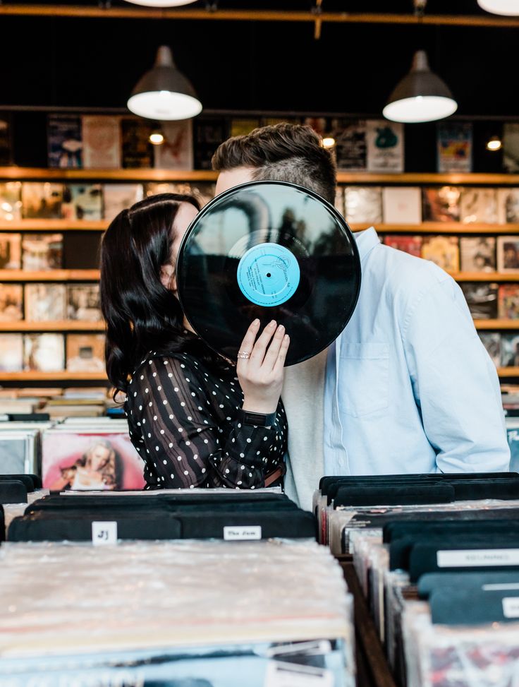 a man and woman kissing in front of record store shelves with records on display behind them