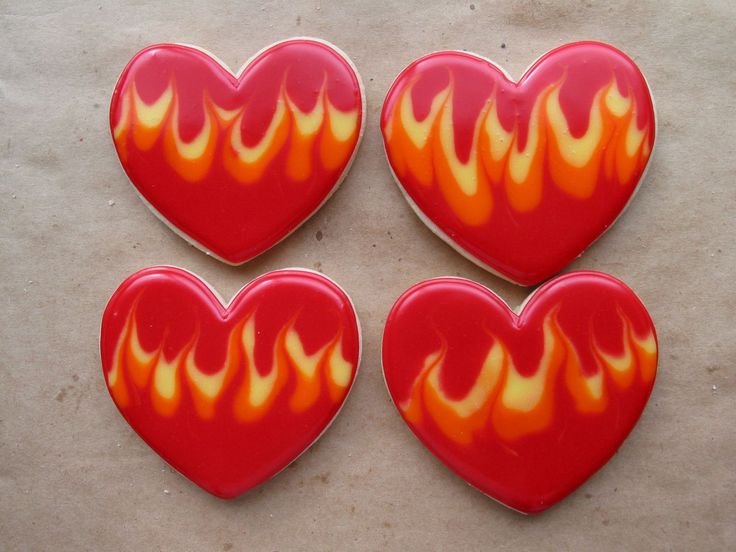 three red hearts with flames on them sitting on top of a white table next to each other