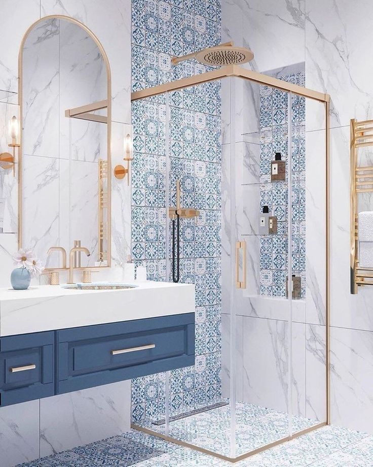 a bathroom with blue and white tiles on the walls, sink, shower stall and mirror