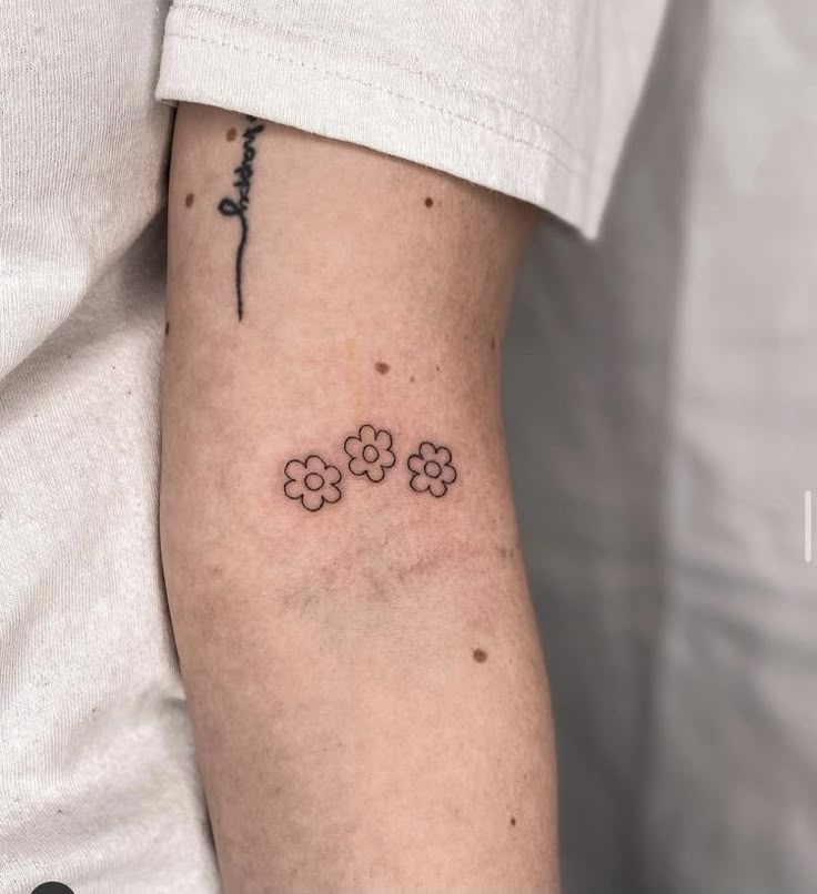 a person with a small tattoo on their arm that has four flowers in the middle