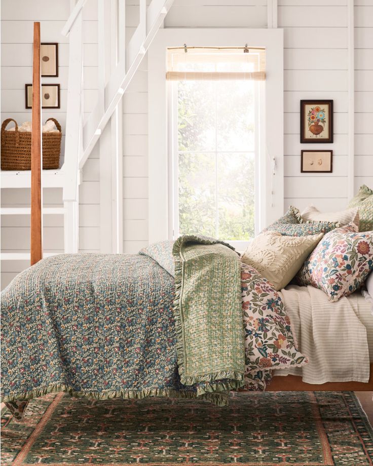 a bed sitting under a window next to a stair case in a room with white walls