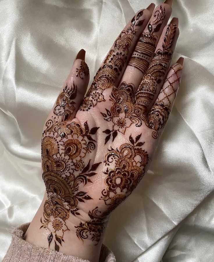 a woman's hands with hennap on top of white sheets and fabric