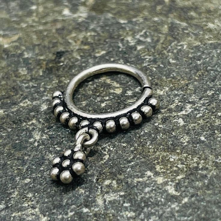 This dazzling silver tribal piece can be worn as a septum, earrings, helix, or tragus . It features a delicate tiny flower hanging in the middle, adding a touch of elegance to any look. 1mm wire - 18 Gauge  Please know your size piercing before making a purchase. All piercings are not returnable due to hygiene and for your safety. Silver Nickel-free Nose Rings, Dainty Nickel-free Nose Rings, Silver Dangle Belly Rings Nickel Free, Nickel-free Silver Dangle Belly Rings, Elegant Adjustable Silver Nose Rings, Nickel-free Silver Dangle Body Jewelry, Silver Internally Threaded Teardrop Piercings, Nickel-free Dangle Belly Rings In Sterling Silver, Adjustable Silver Toe Ring Piercings